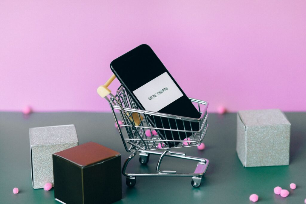 Cell phone in miniature shopping cart to represent ecommerce