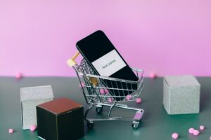 Cell phone in miniature shopping cart to represent ecommerce