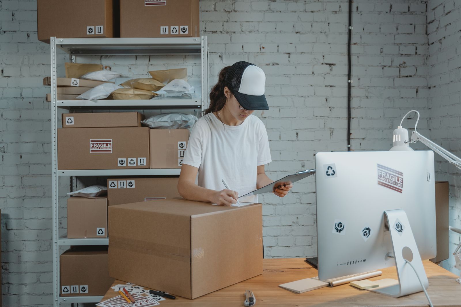 Ecommerce operations employee recording carton details on a clipboard during a manual inventory reconciliation