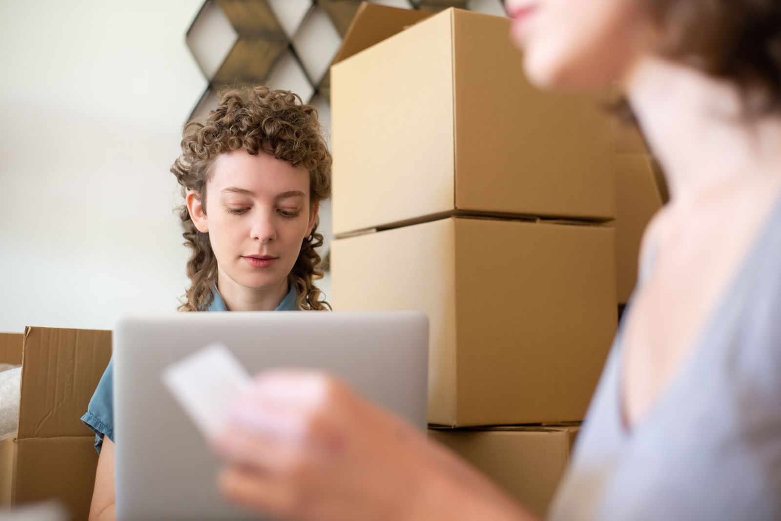 Small ecommerce team reviewing order and inventory workflows on a laptop while surrounded by shipping cartons