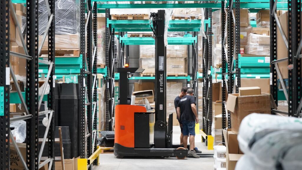 Warehouse team and forklift operator moving inventory in a modern fulfillment center supported by a Shopify ERP integration