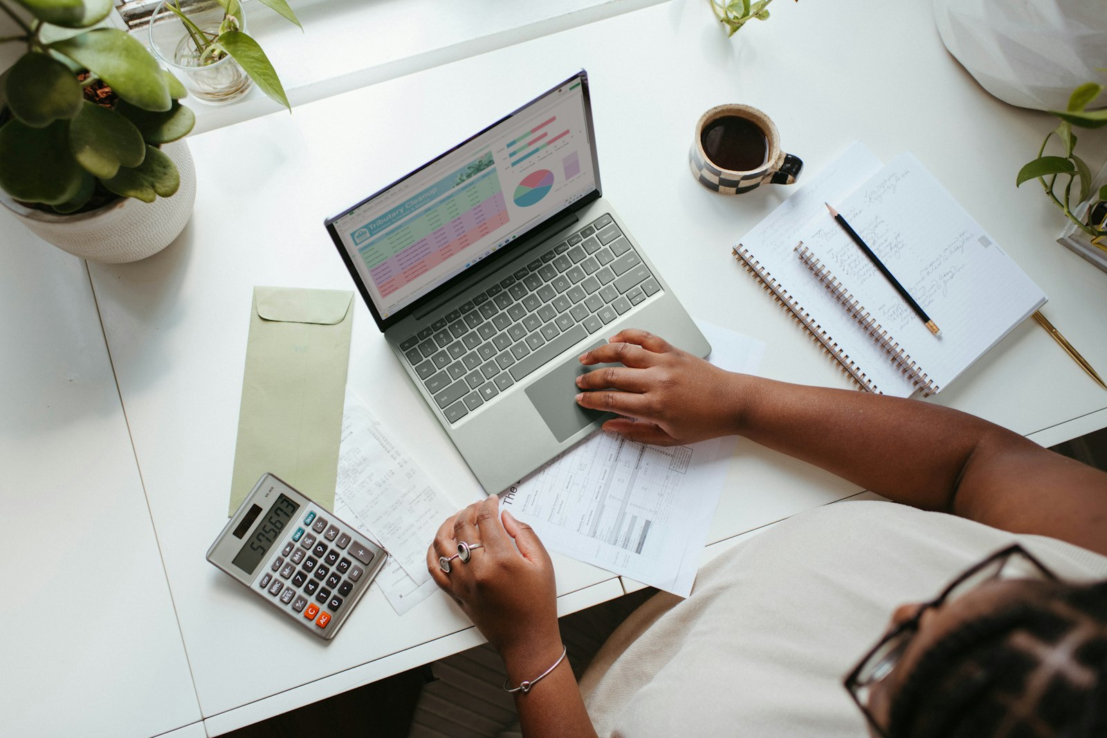 Merchant comparing Shopify development budgets with a laptop, calculator, and project notes