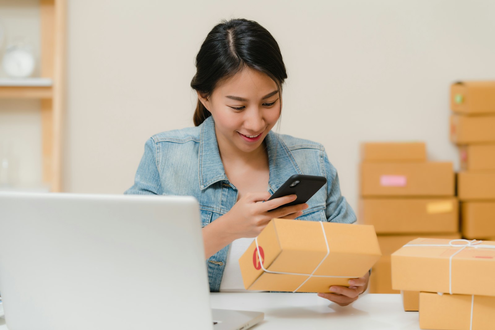 Small business owner packing online orders beside a laptop while reviewing store performance
